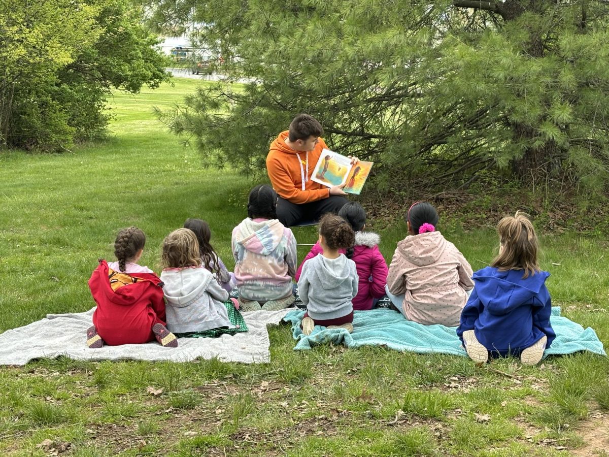 Enact Club member, Benjamin Tucker, reading to kindergarten students at the annual Hop Into Spring event.  