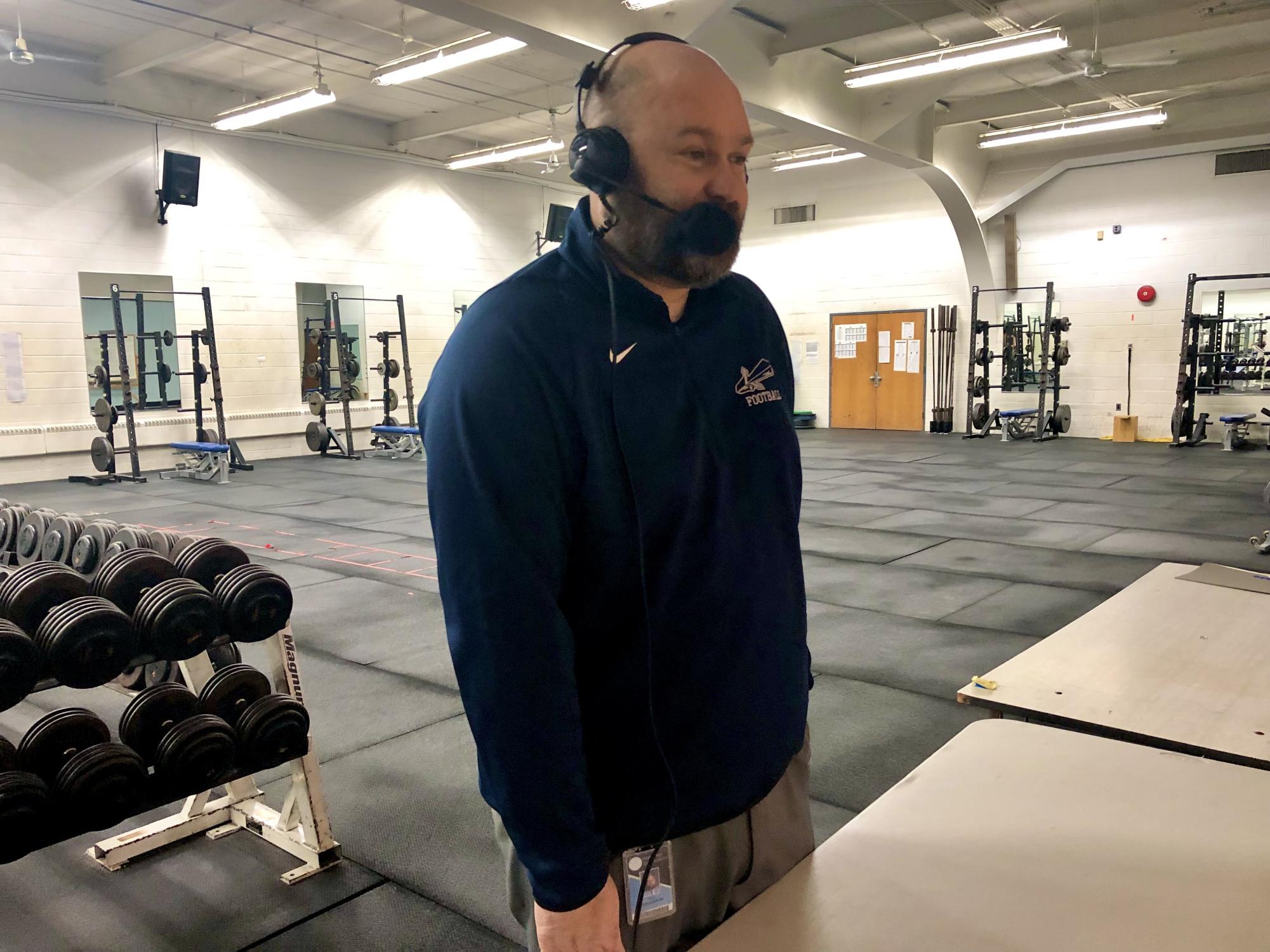 Principal Kyle Hassler looks over the basketball court from above in the weight room in preperation to call a game.