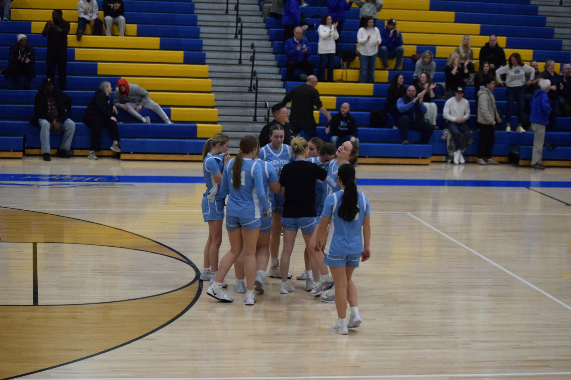 The North Penn girls circle around Cam Crowley after the final buzzer of their season.