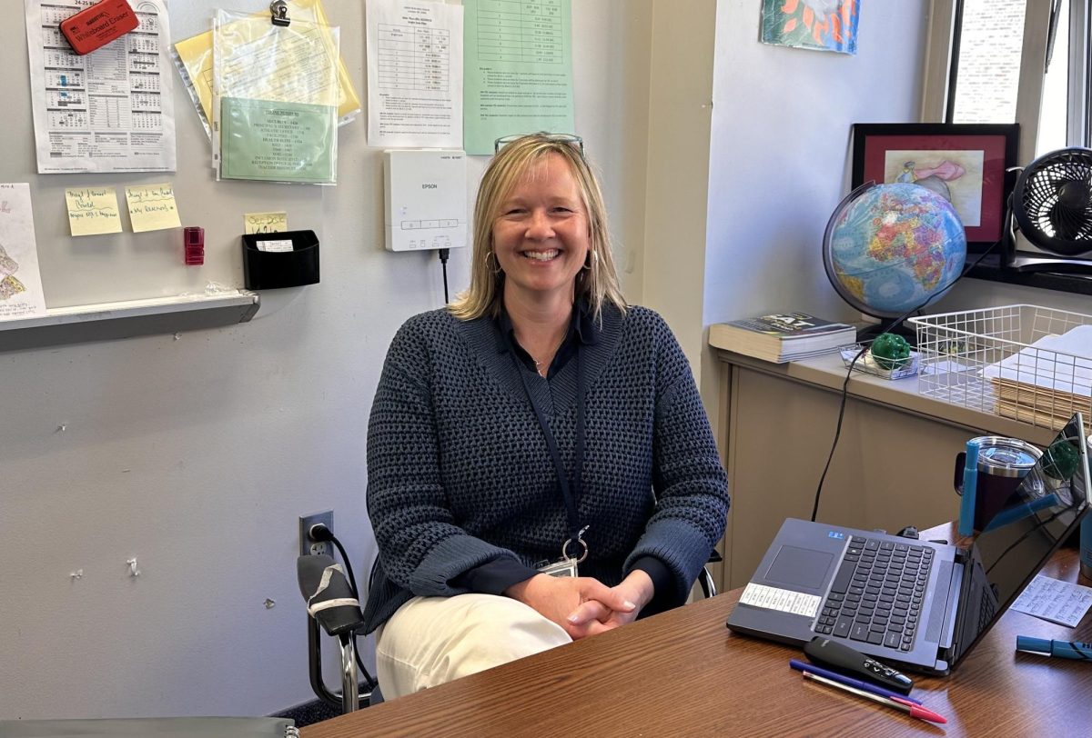 Mrs Schmidt joyfully sitting in her classroom, ready to begin another great day of teaching!